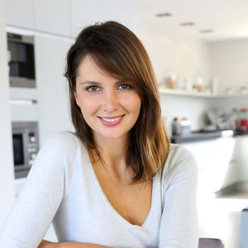 young woman sitting at a kitchen table with planner and tablet