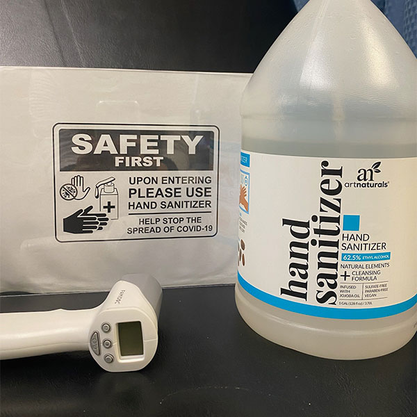 Sign for Safety First with jug of sanitizer and thermometer